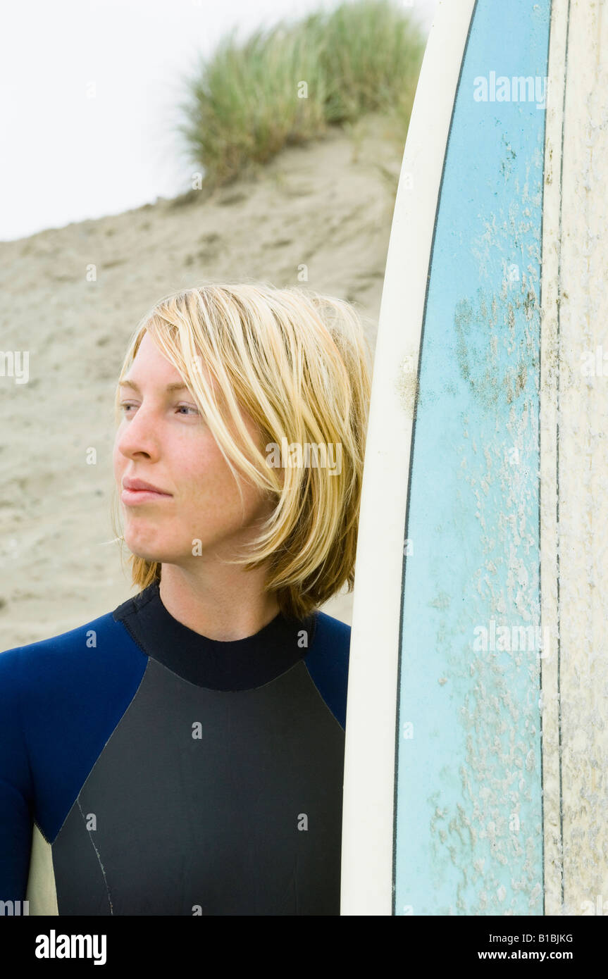 Surfeur Blond femme en combinaison avec le bleu avec un surf plage du  nord-ouest du Pacifique dans l'arrière-plan Photo Stock - Alamy