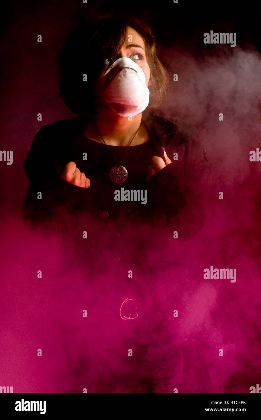 Femme en masque médical à l'intérieur de nuages de fumée Banque D'Images