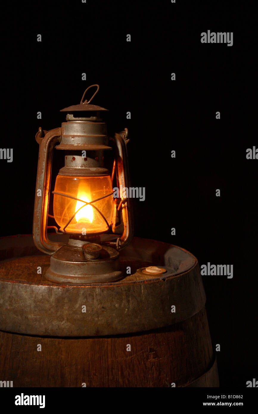 Une lampe à huile debout sur un tonneau dans les ténèbres. Banque D'Images