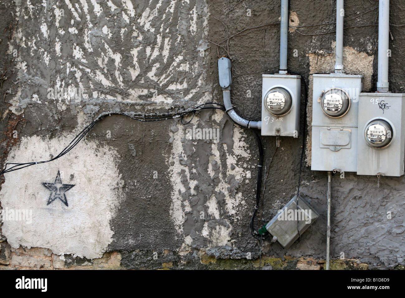 Un mur décoré avec trois compteurs électriques et un pochoir graffiti. Banque D'Images