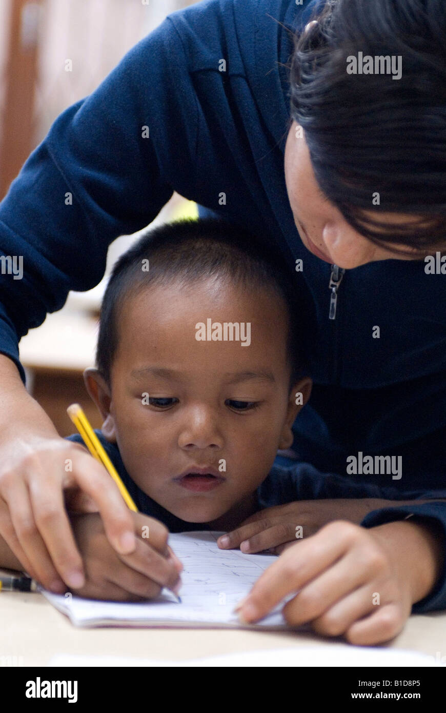 Jeune garçon l'apprentissage de l'écriture avec l'aide d'un professeur, Katmandou, Népal Banque D'Images
