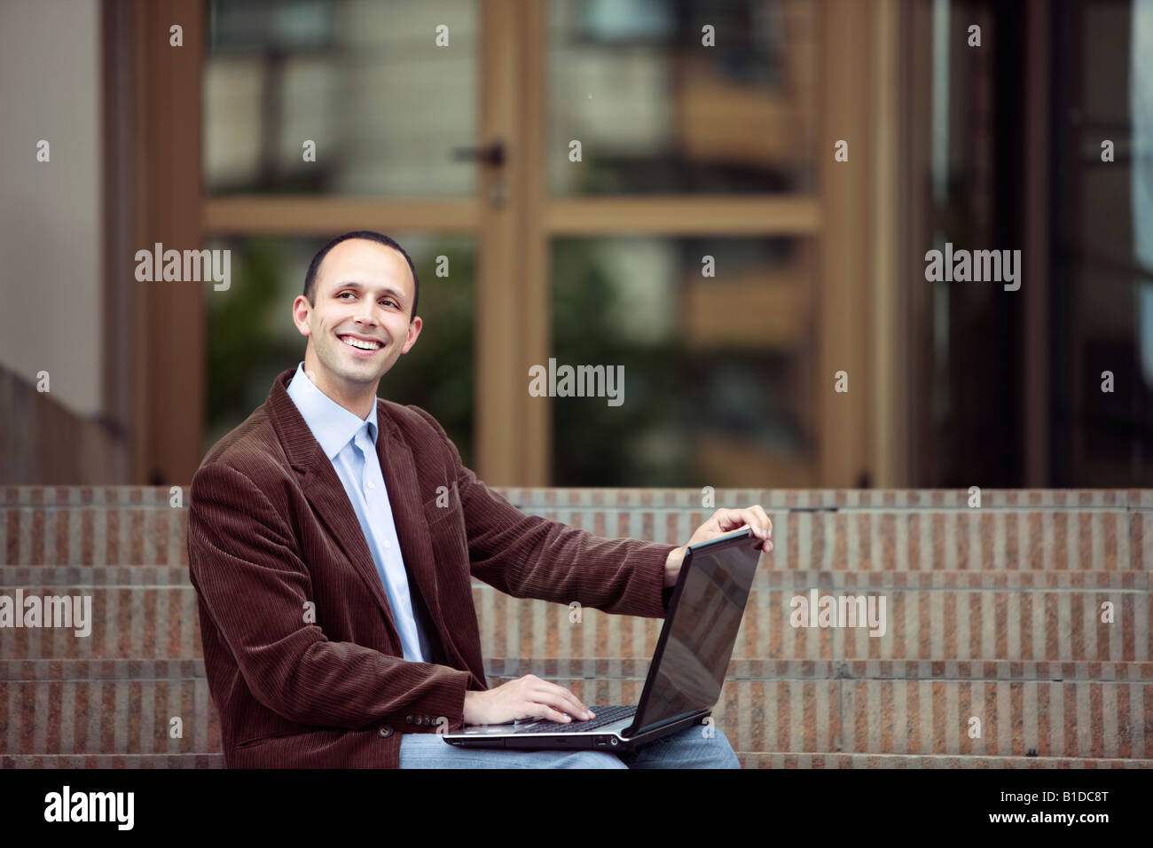 Jeune homme d'affaires à la hauteur avec un ordinateur portable en face d'un bâtiment Banque D'Images