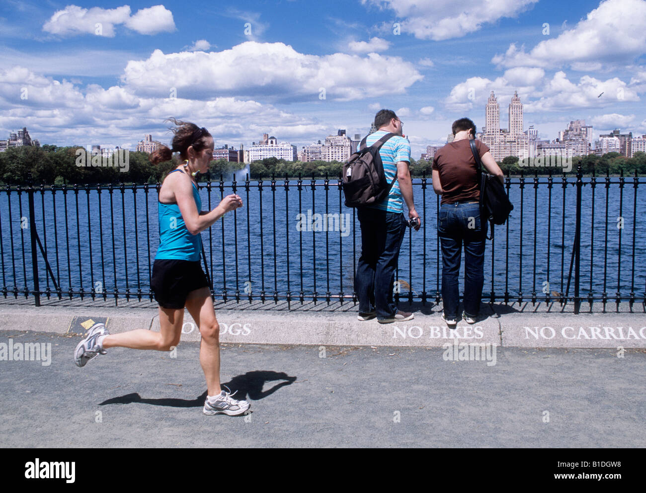 Réservoir Jacqueline Kennedy Onassis ou réservoir Central Park. Femme jogger et deux hommes vous avec des sacs de tricot. Horizon de Central Park West Banque D'Images