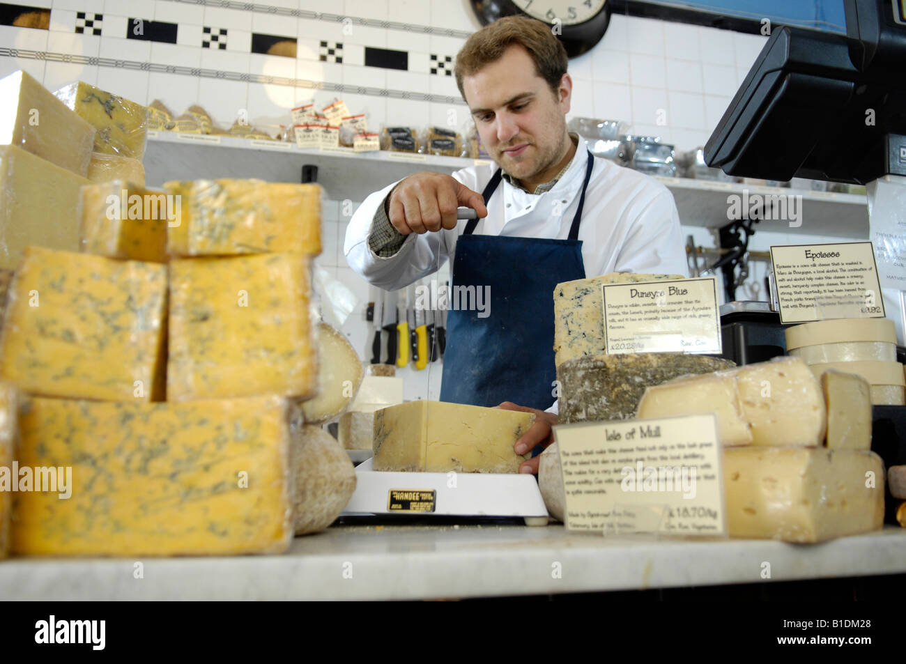 Fromager la découpe du fromage en boutique traditionnelle Banque D'Images