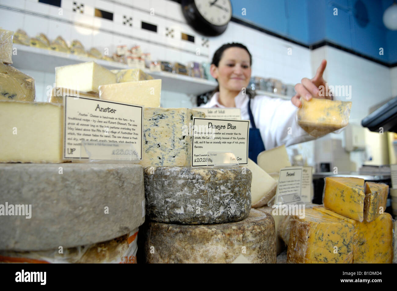 Fromager derrière comptoir avec du fromage en boutique traditionnelle Banque D'Images