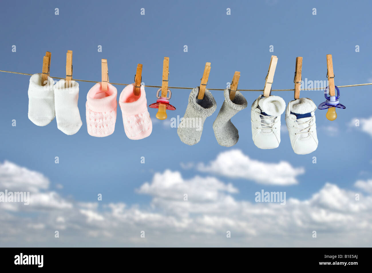 Chaussettes et chaussures bébé suspendu à une corde dans le ciel Banque D'Images
