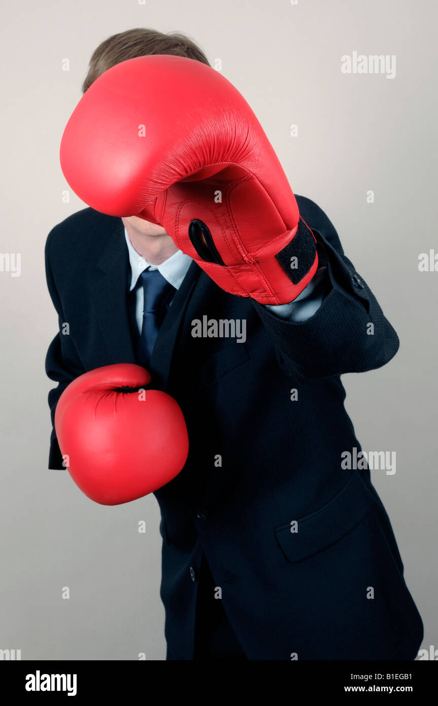 Businessman holding red boxing gloves in front of face Banque D'Images