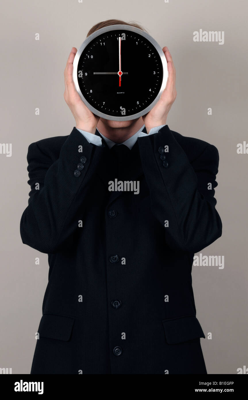 Businessman holding une horloge en face de visage Banque D'Images