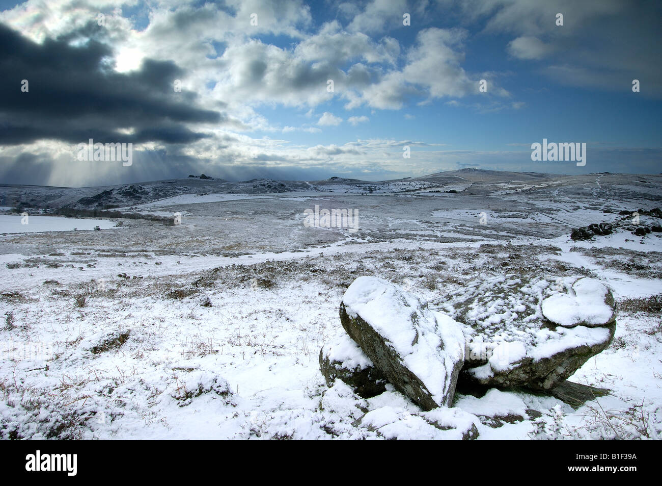 Le poids de la neige près de Chinkwell Tor sur le parc national du Dartmoor avec deux rochers de granit à l'avant-plan et un ciel d'orage Banque D'Images