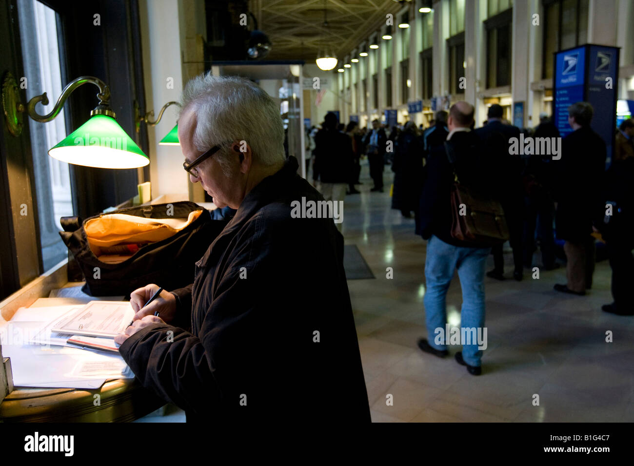 Un homme remplit son formulaire d'impôt dans le hall du Farley Bureau de poste à New York le jour de l'impôt 15 avril 2008 Banque D'Images