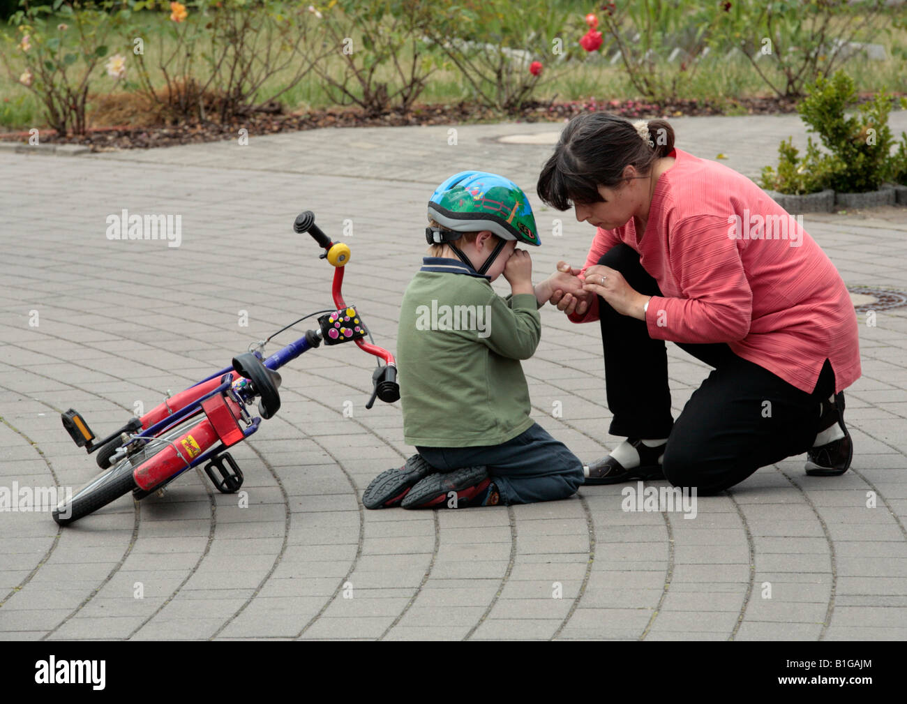 Mère réconfortant son jeune fils après qu'il s'est écrasé avec son vélo Banque D'Images