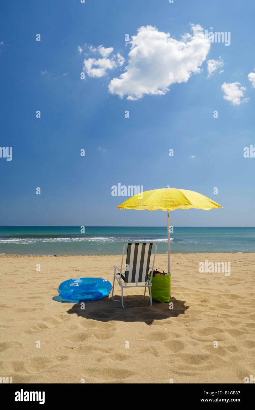 Un parasol jaune et du matériel de plage sur une plage de sable au bord de la mer en été. La Mata, Torrevieja, Espagne. Banque D'Images