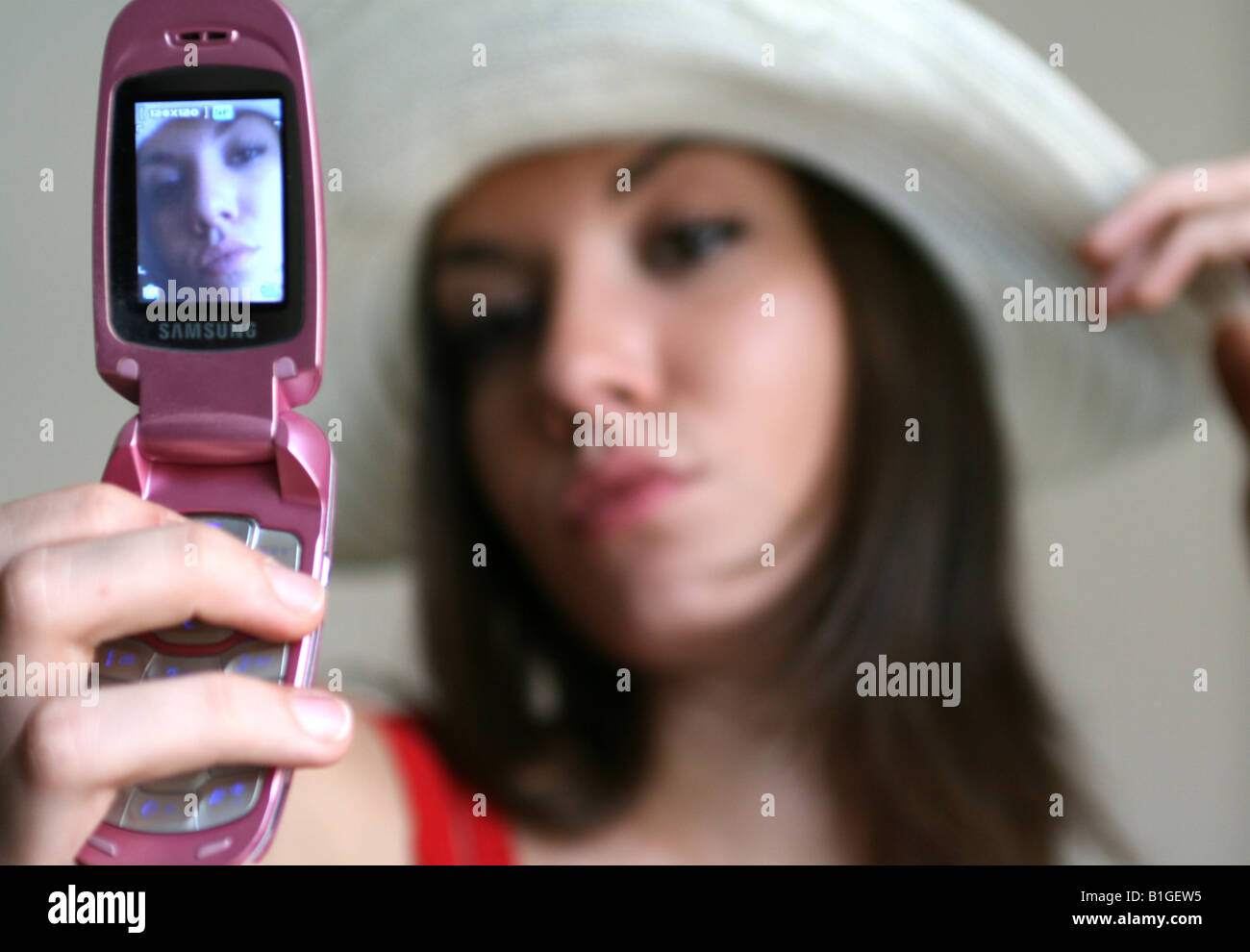 Young woman holding photograph with mobile phone Banque D'Images