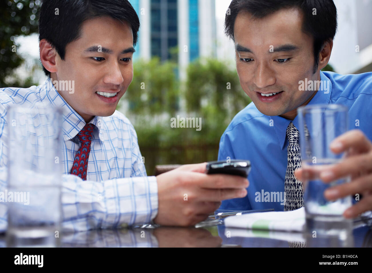 Deux business man using mobile phone in outdoor cafe Banque D'Images
