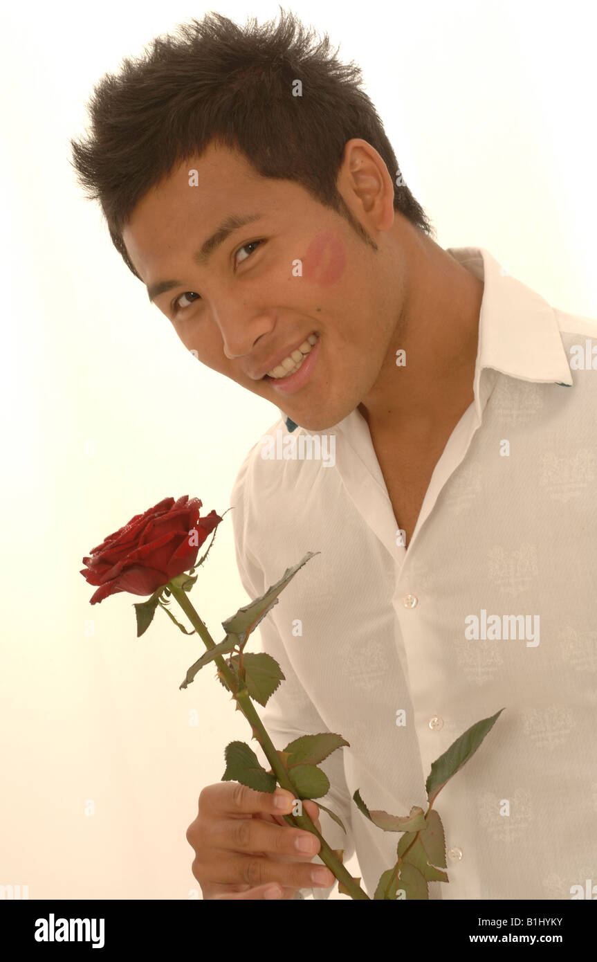 L'homme asiatique avec une rose rouge et kissmouth sur son chèque Banque D'Images