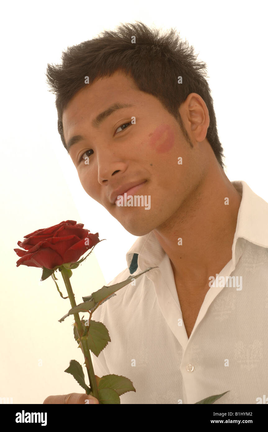 L'homme asiatique avec une rose rouge et kissmouth sur son chèque Banque D'Images