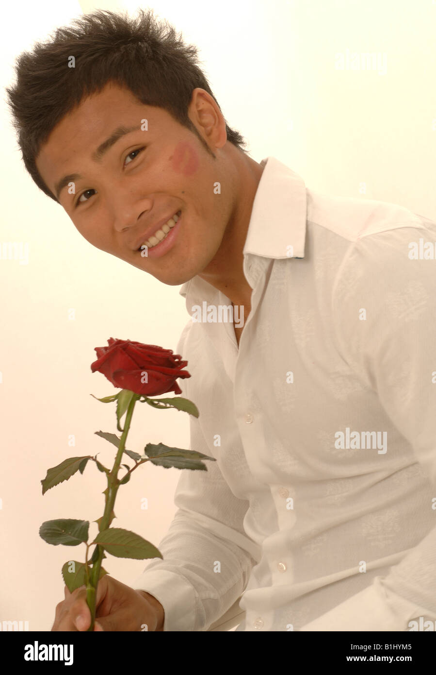 L'homme asiatique avec une rose rouge et kissmouth sur son chèque Banque D'Images