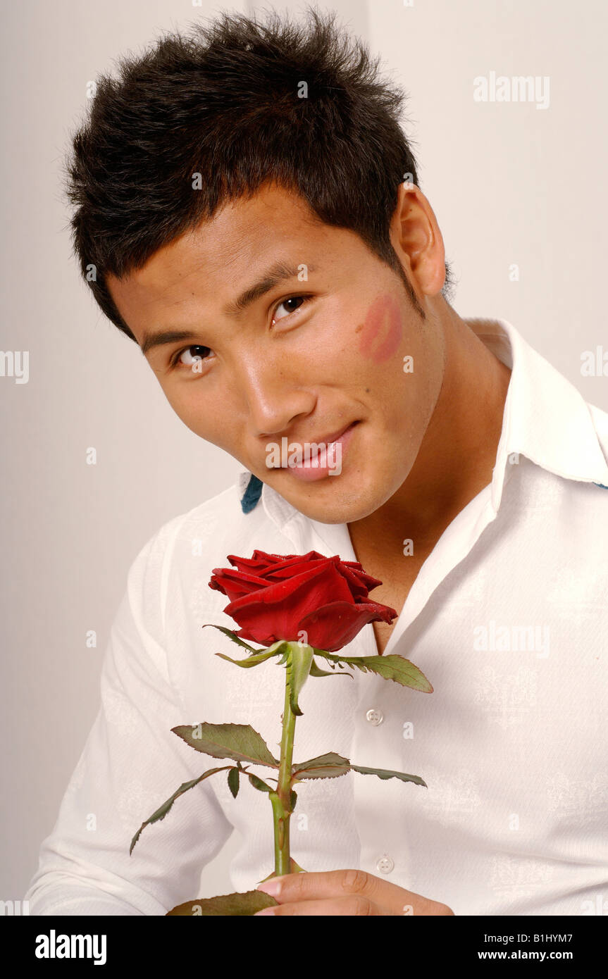 L'homme asiatique avec une rose rouge et kissmouth sur son chèque Banque D'Images
