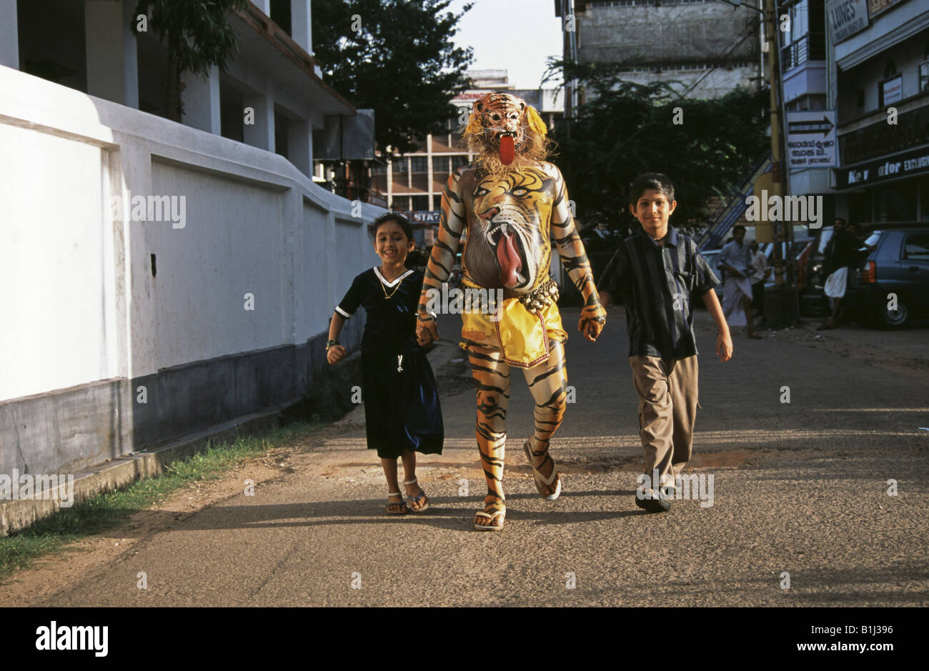 Puli Kali dancer marcher avec une fille et un garçon dans une rue, Pulikali, Kerala, Inde Banque D'Images