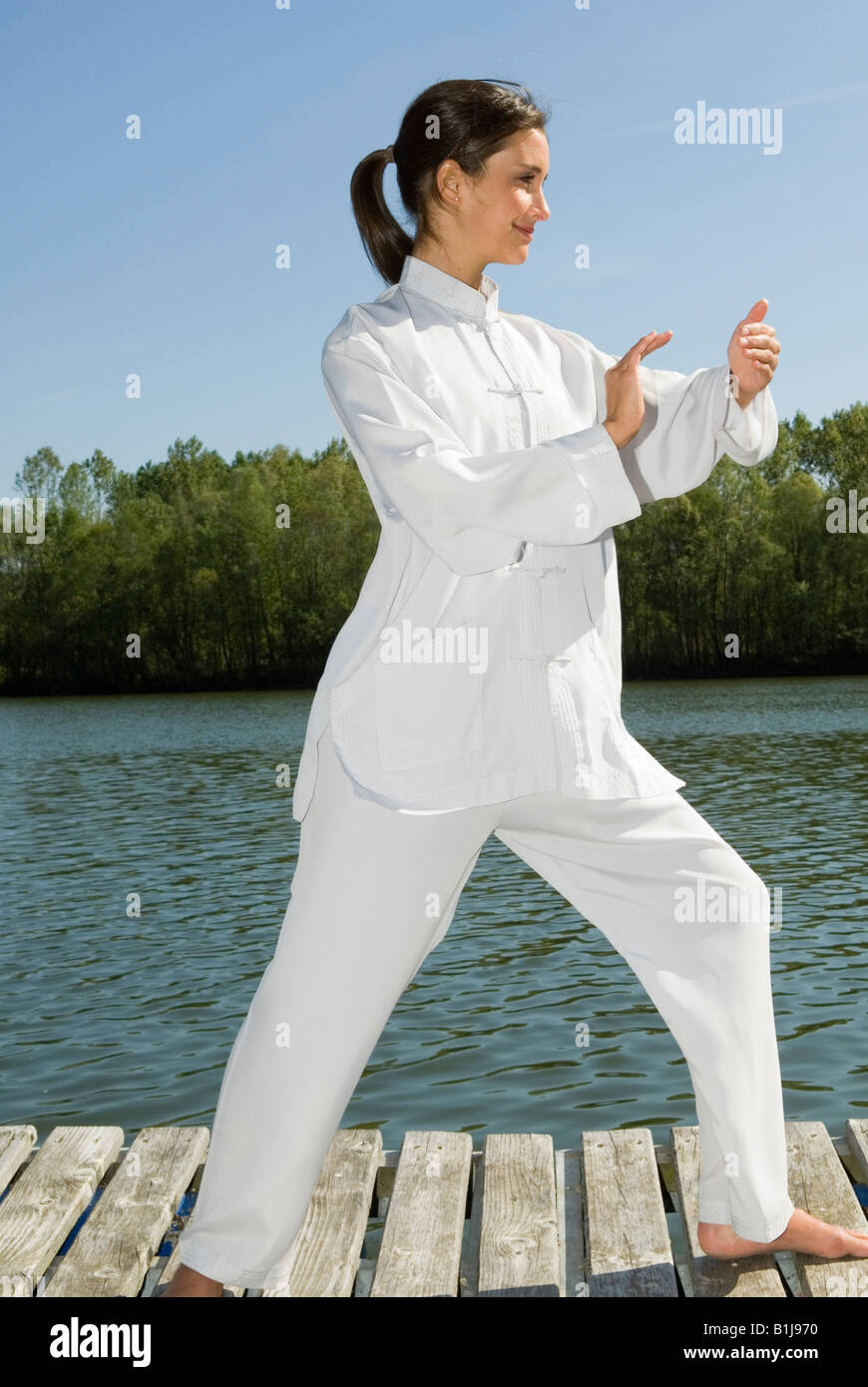 Young Pretty woman practicing Tai Chi sur une promenade sur un lac, saisissez la queue des oiseaux Banque D'Images