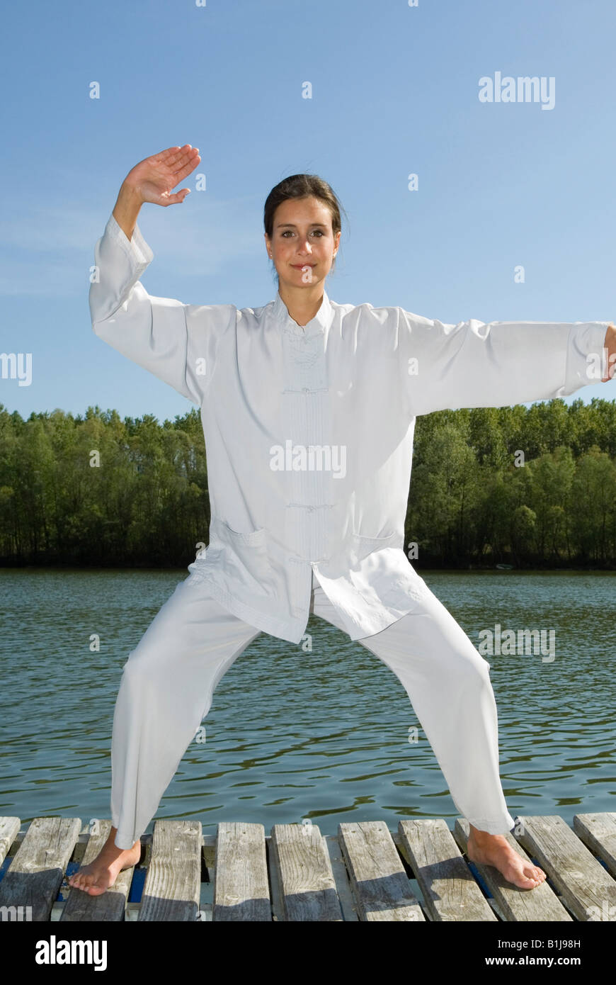 Young Pretty woman practicing Tai Chi sur une promenade au bord d'un lac Banque D'Images
