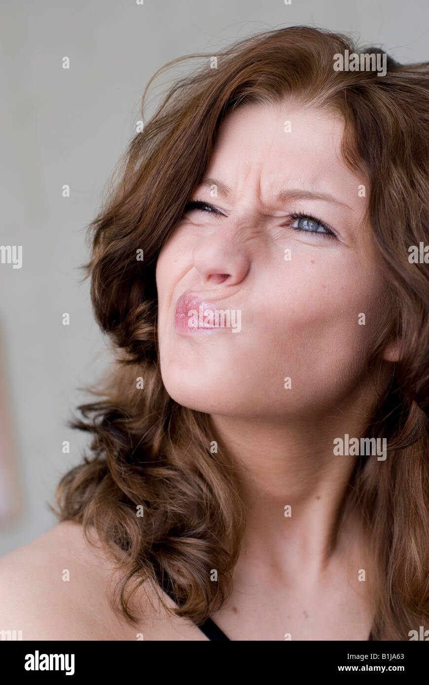 Belle jeune femme aux cheveux bruns frisés, gurning Banque D'Images