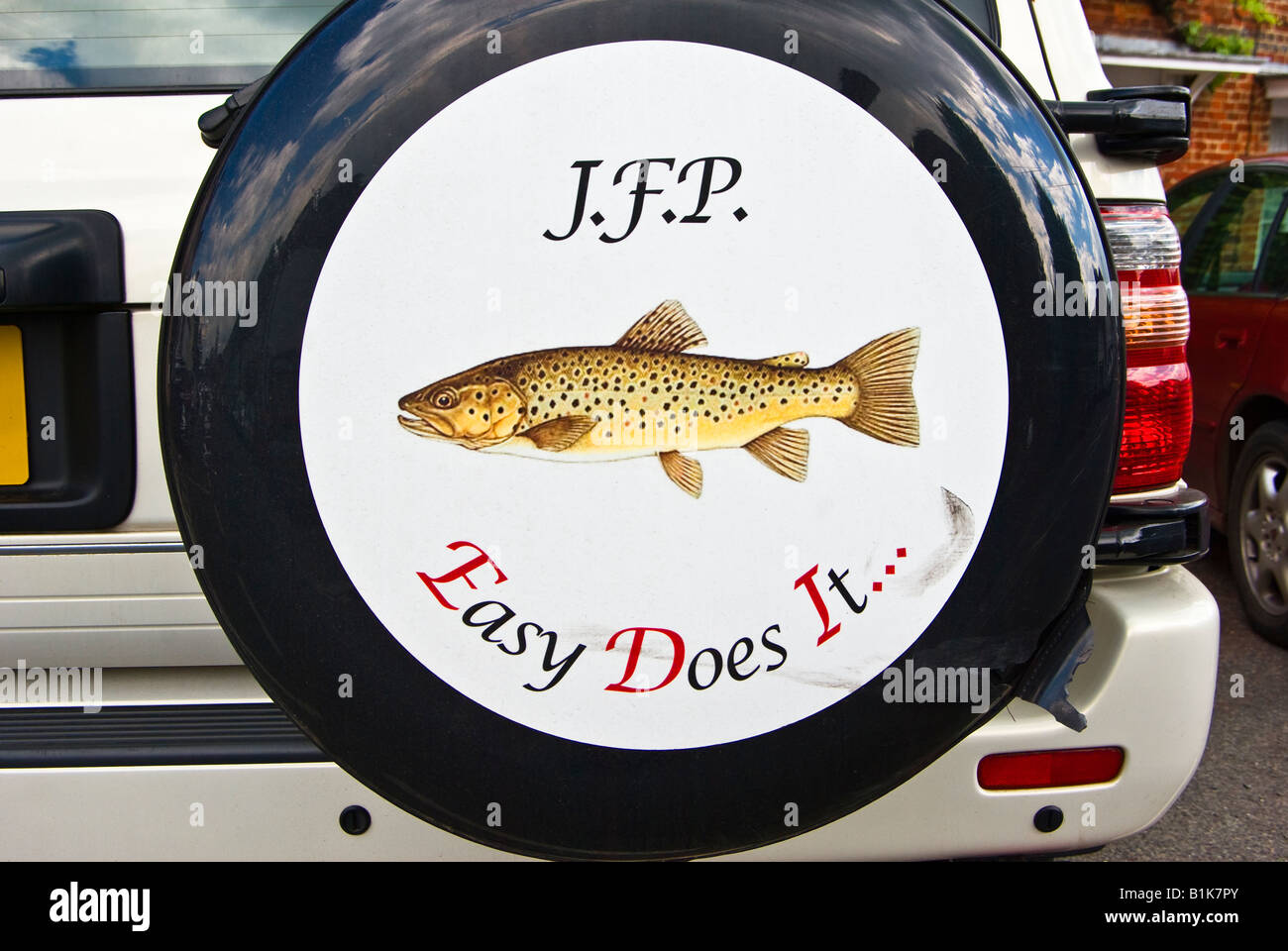 Photo d'un poisson la truite sur un cache roue de secours sur une voiture garée Banque D'Images