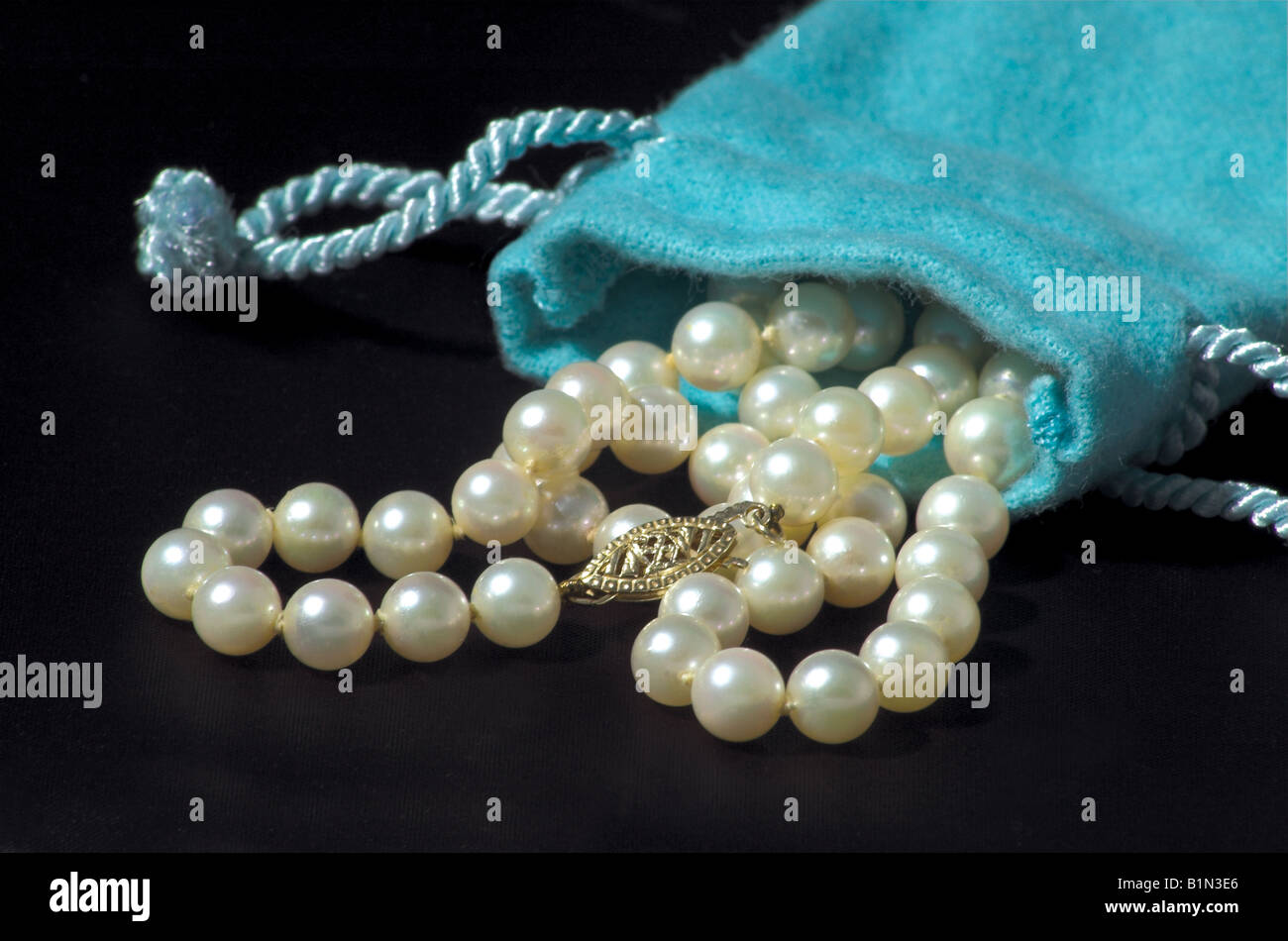 Collier de perles de tomber d'un sac de style Tiffany turquoise sur fond noir. Banque D'Images