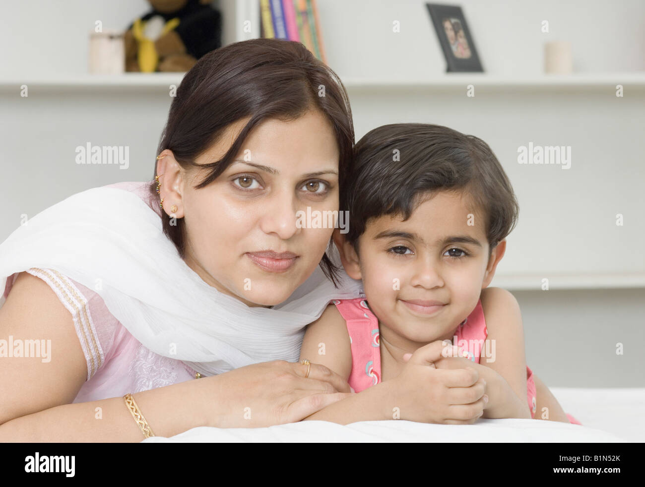 Portrait of a Mid adult woman with her daughter lying on the bed Banque D'Images