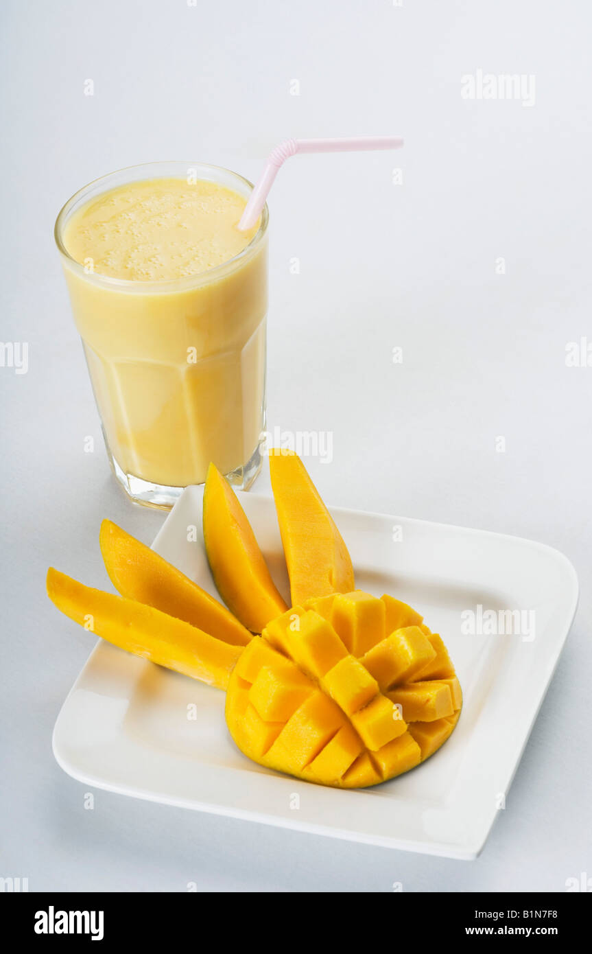 Close-up of a les tranches de mangue dans un plat avec un verre de mango shake Banque D'Images