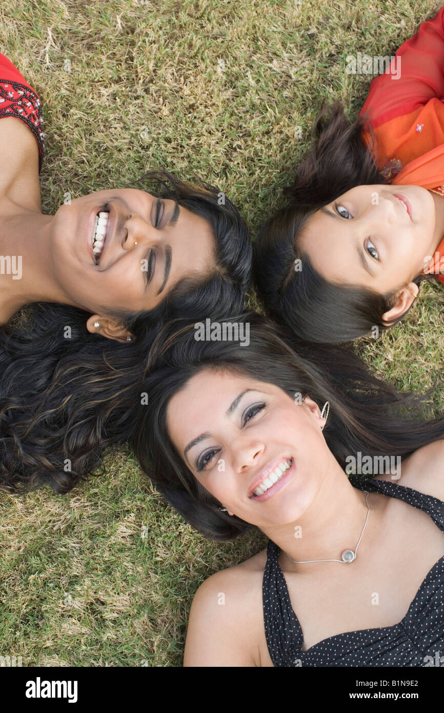 Deux jeunes femmes avec une fille couchée dans un cercle sur l'herbe et smiling Banque D'Images