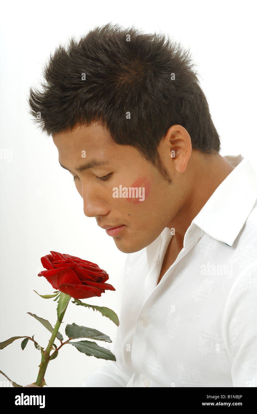 L'homme asiatique avec une rose rouge et une kissmouth sur son chèque Banque D'Images