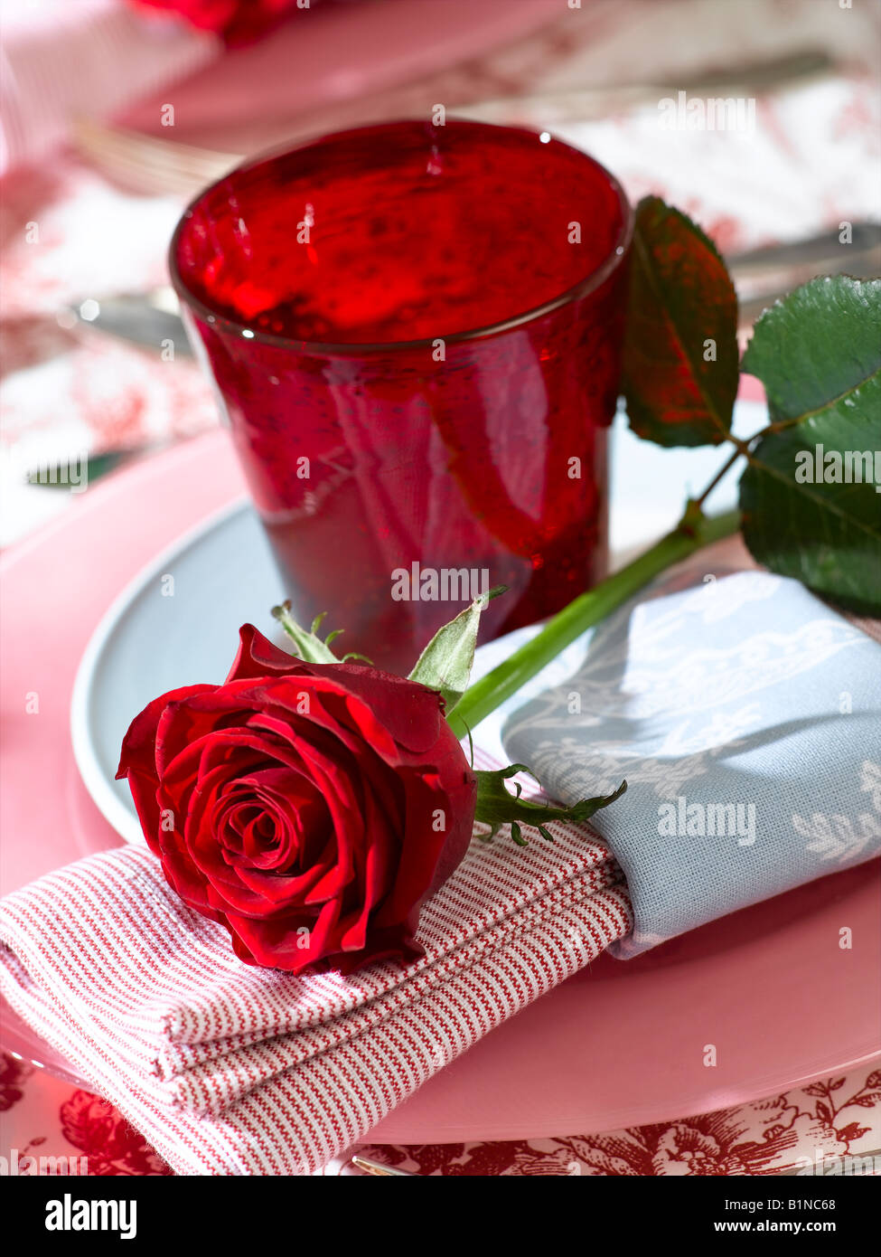 Place avec un verre de rouge et une rose rouge Banque D'Images