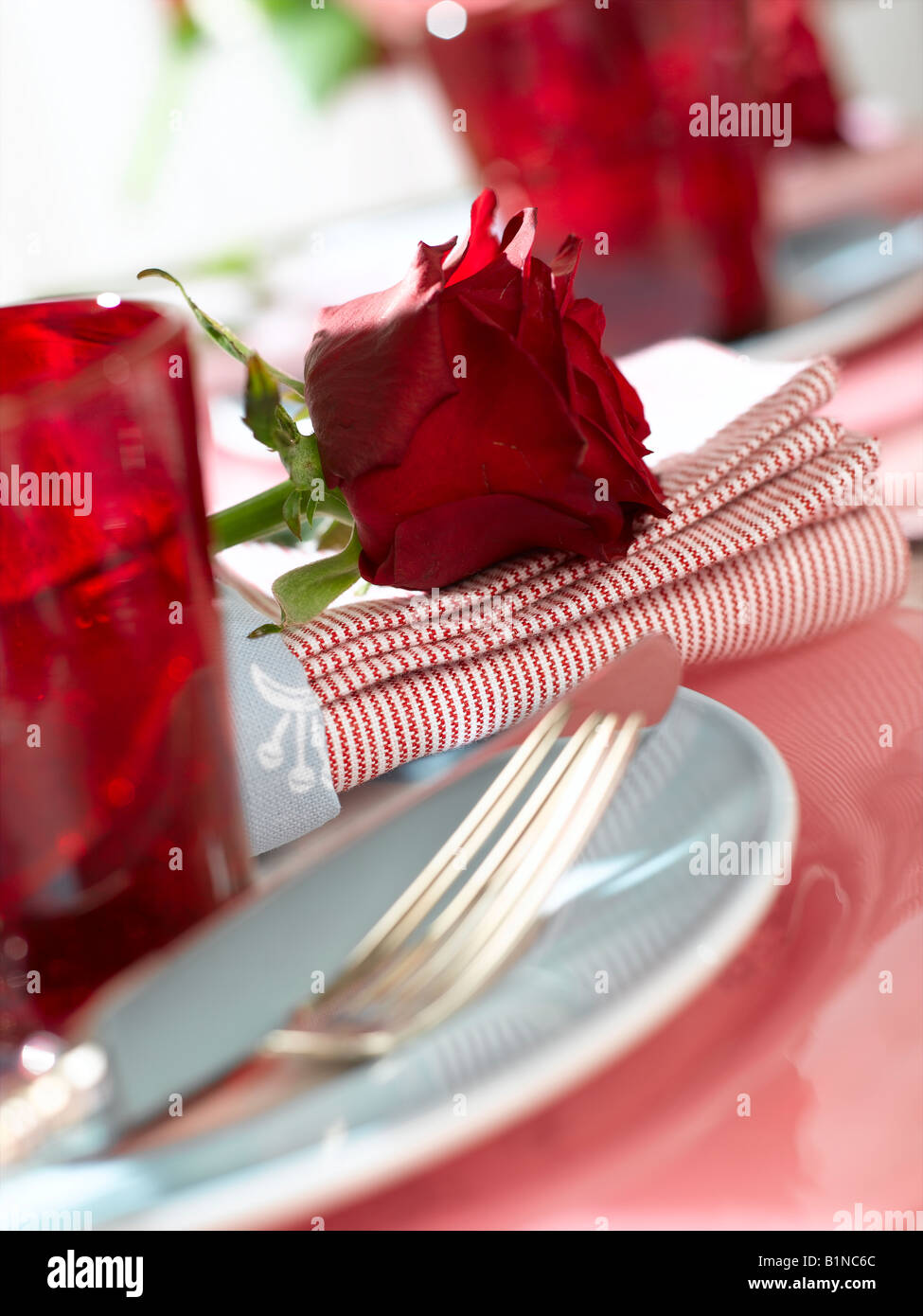 Place avec un verre de rouge et une rose rouge Banque D'Images