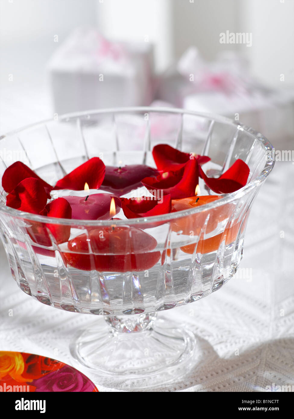 La disposition des pétales de rose rouge et d'une des bougies dans un bol en verre Banque D'Images