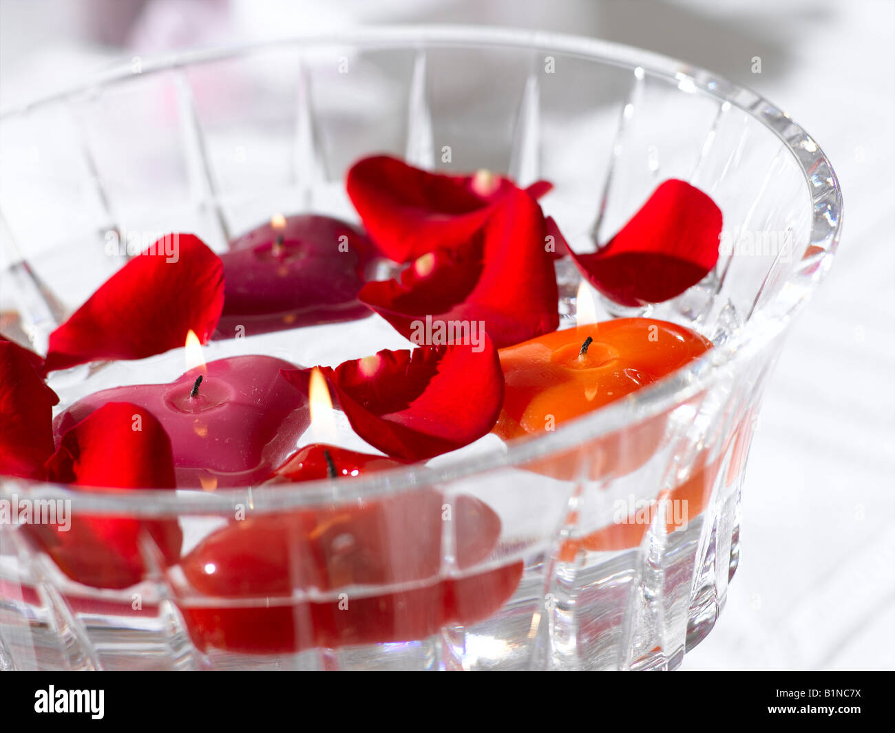 La disposition des pétales de rose rouge et d'une des bougies dans un bol en verre Banque D'Images