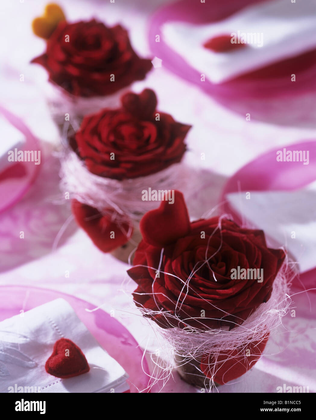 Décoration de table avec des roses rouges dans les petits pots et coeurs rouges Banque D'Images