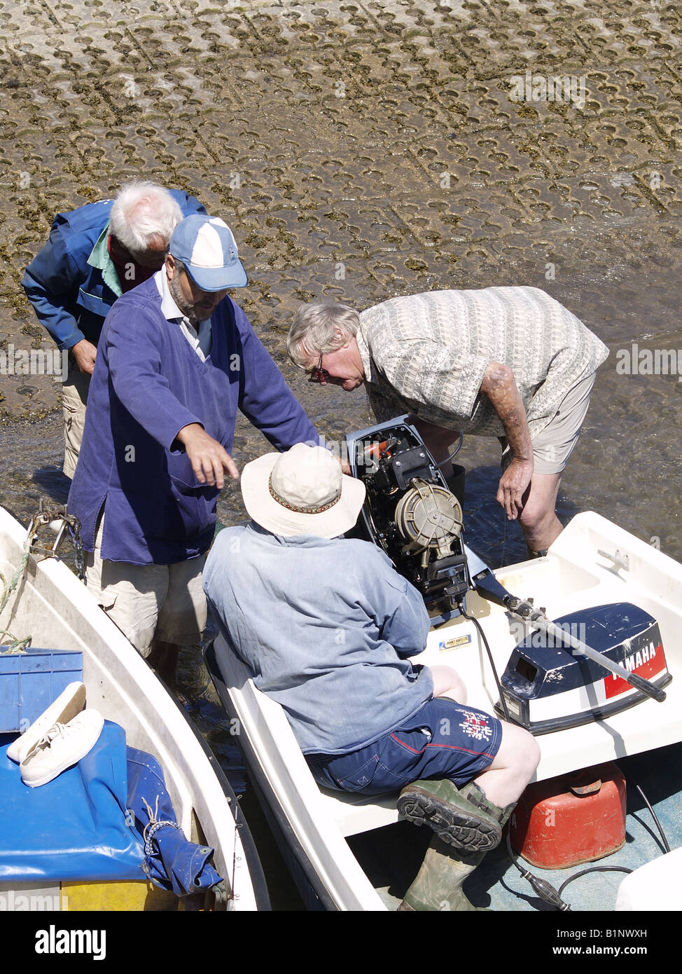 Quatre vieillards à essayer de réparer un moteur hors-bord Banque D'Images