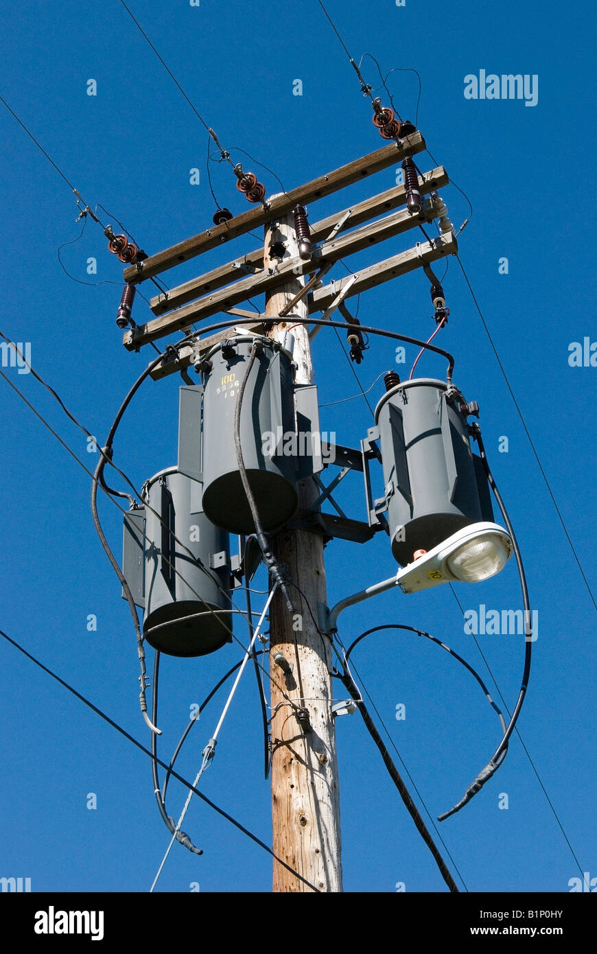 Poteau électrique avec transformateurs et lignes électriques contre un ciel bleu clair Banque D'Images