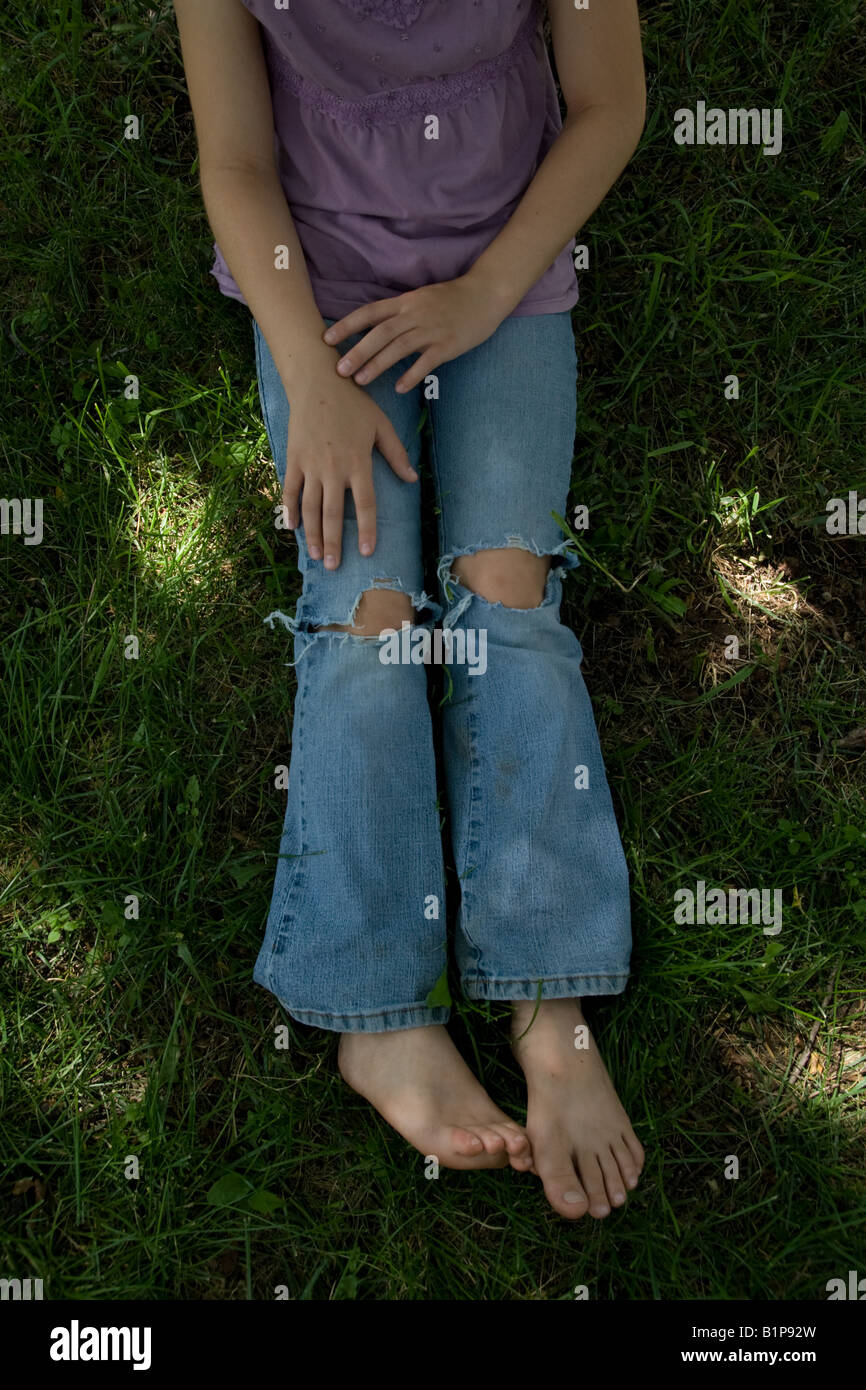 Une jeune fille portant des jeans avec des trous dans les genoux Photo  Stock - Alamy