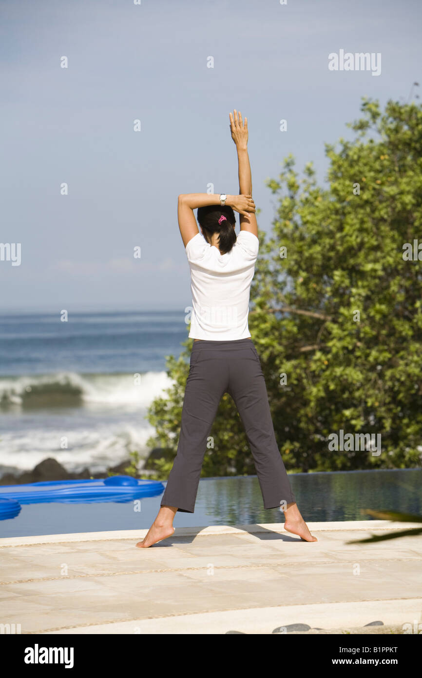 Asian woman exerçant sur la terrasse de la piscine Banque D'Images