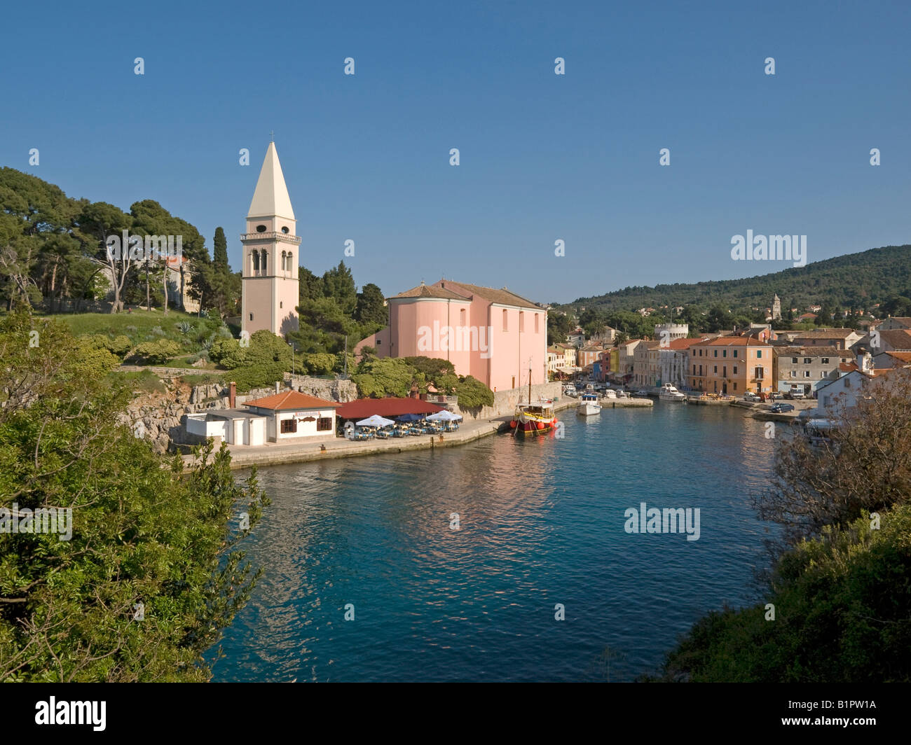 Église à la baie dans le bassin du port avec des bateaux de pêcheurs et des bateaux à moteur dans la ville Veli Losinj sur l'île de Losinj Banque D'Images