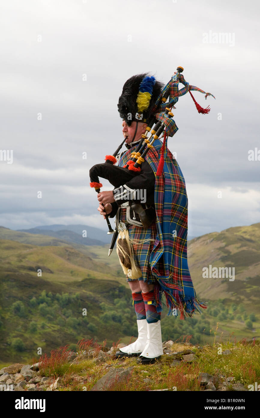 Piper écossais jouer de la cornemuse et portant sur kilt en tartan hill-tops de Invernesshire, Scotland UK Banque D'Images