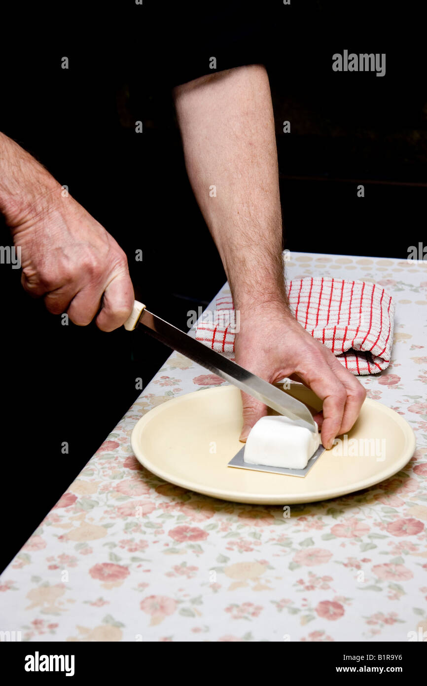 A 60yr old man's hands couper un peu / mini gâteau avec un long couteau Banque D'Images