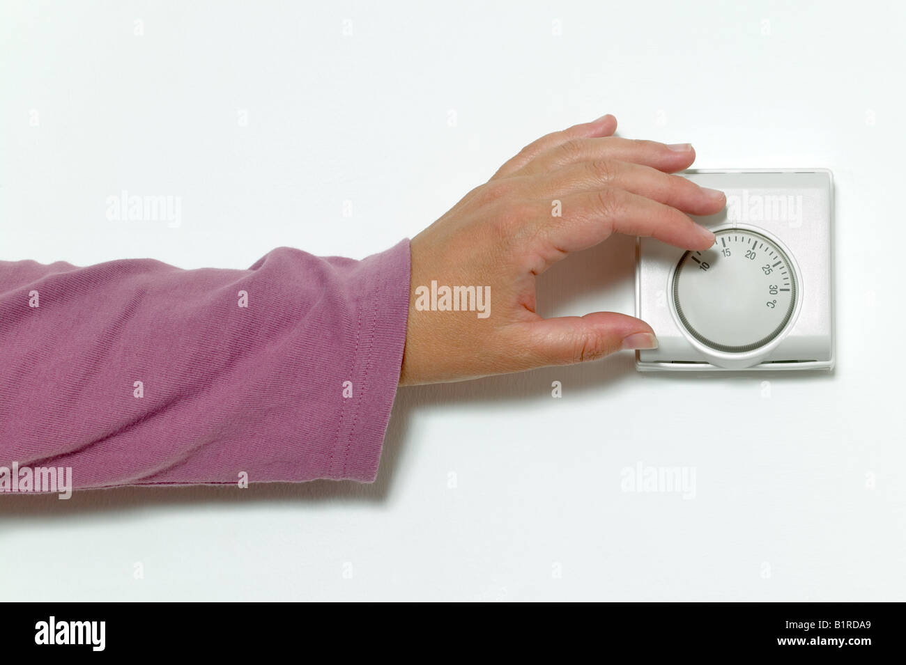 La main de femme de baisser le thermostat sur une température Banque D'Images