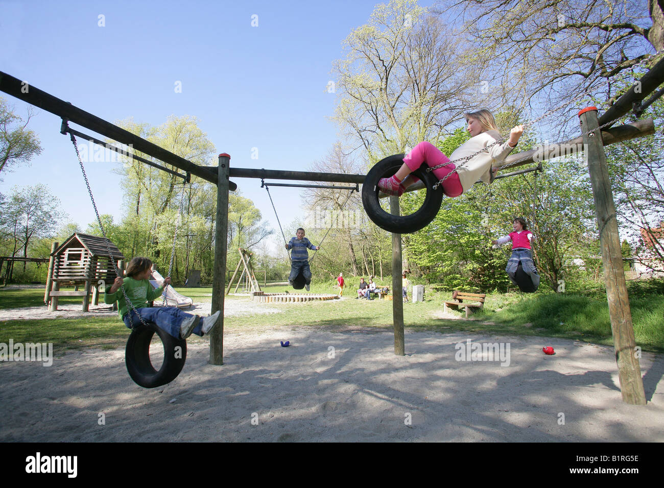 Les enfants se balançant sur pneu de voiture pivote à une aire de jeux dans Muehldorf am Inn, Upper Bavaria, Bavaria, Germany, Europe Banque D'Images