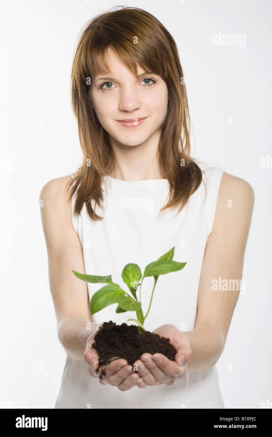 Jeune femme prenant un jeune plant enraciné dans le sol dans ses mains Banque D'Images