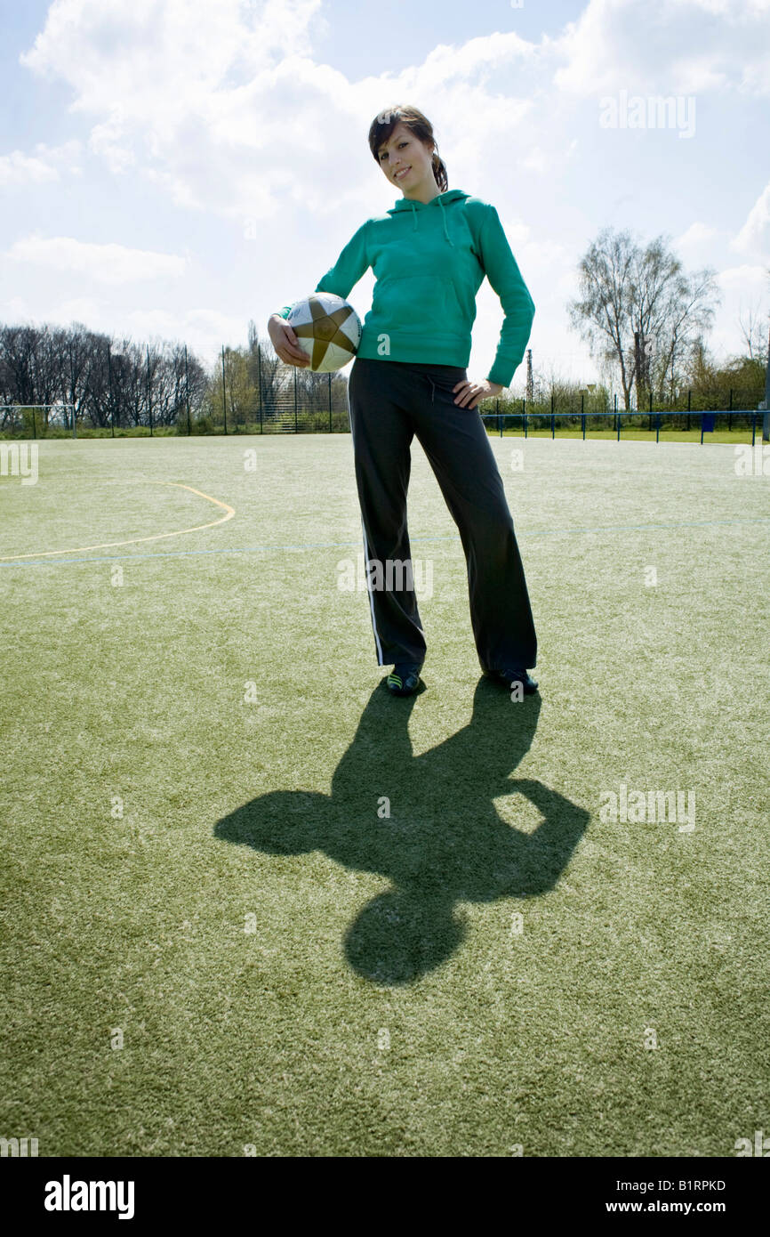 Jeune femme debout sur un terrain de sport holding a football Banque D'Images