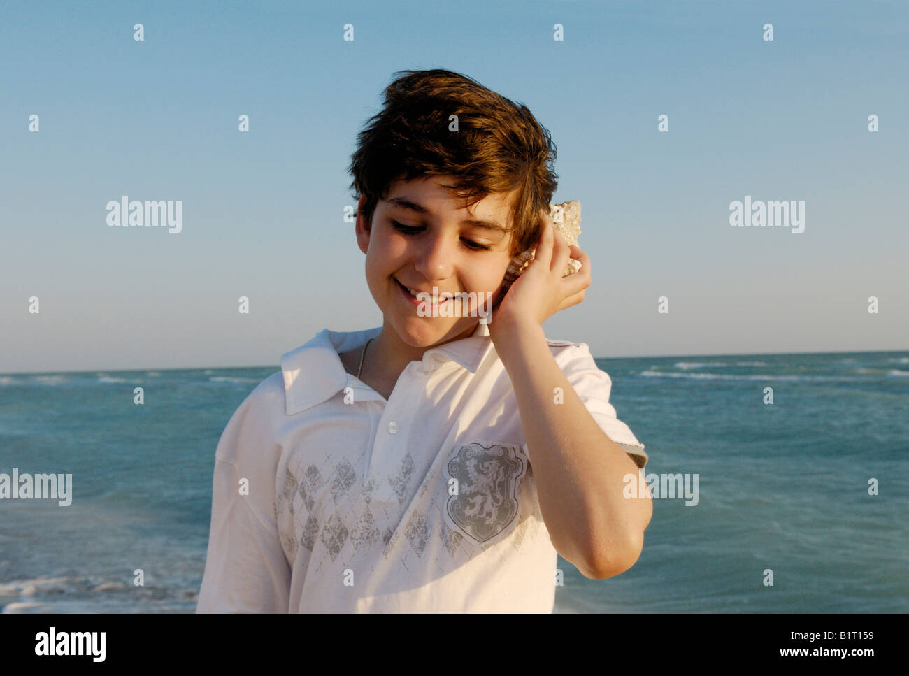 Boy listening to seashell Banque D'Images