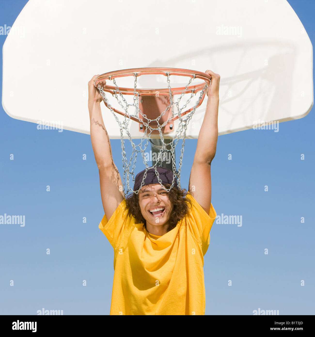 Un joueur de basket-ball de l'adolescence se bloque à partir d'un panier de basket-ball et de sourires Banque D'Images